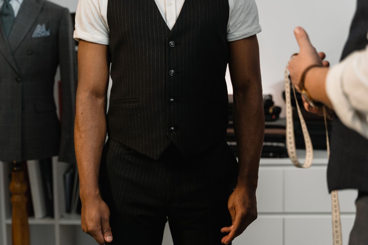 A well-fitting suit jacket laid flat on a table with a tape measure across the shoulder seam, used as a reference for sizing