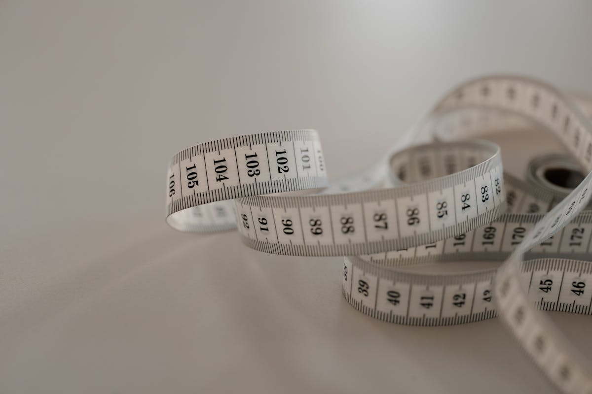 Close-up of a soft fabric sewing tape measure coiled on a wooden tailor's table at a Hoi An tailor