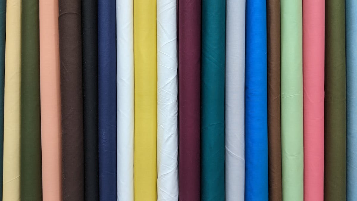 Colorful fabric rolls in a Hoi An tailor shop with natural light streaming through the entrance