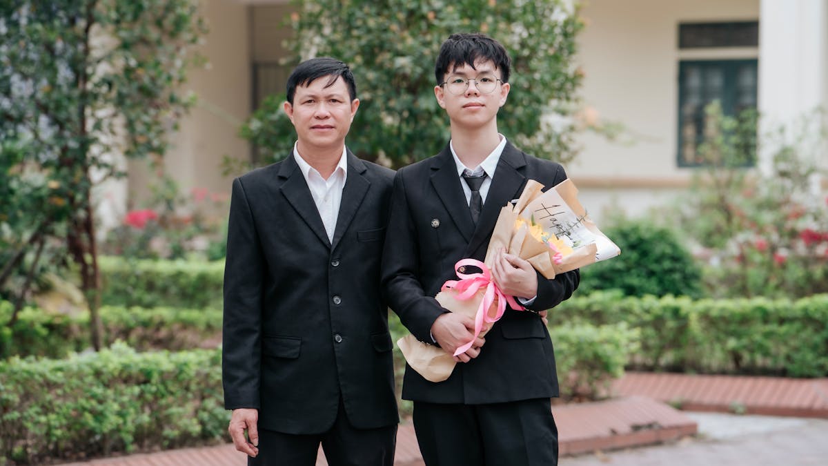Father and son in suits celebrating graduation day outdoors